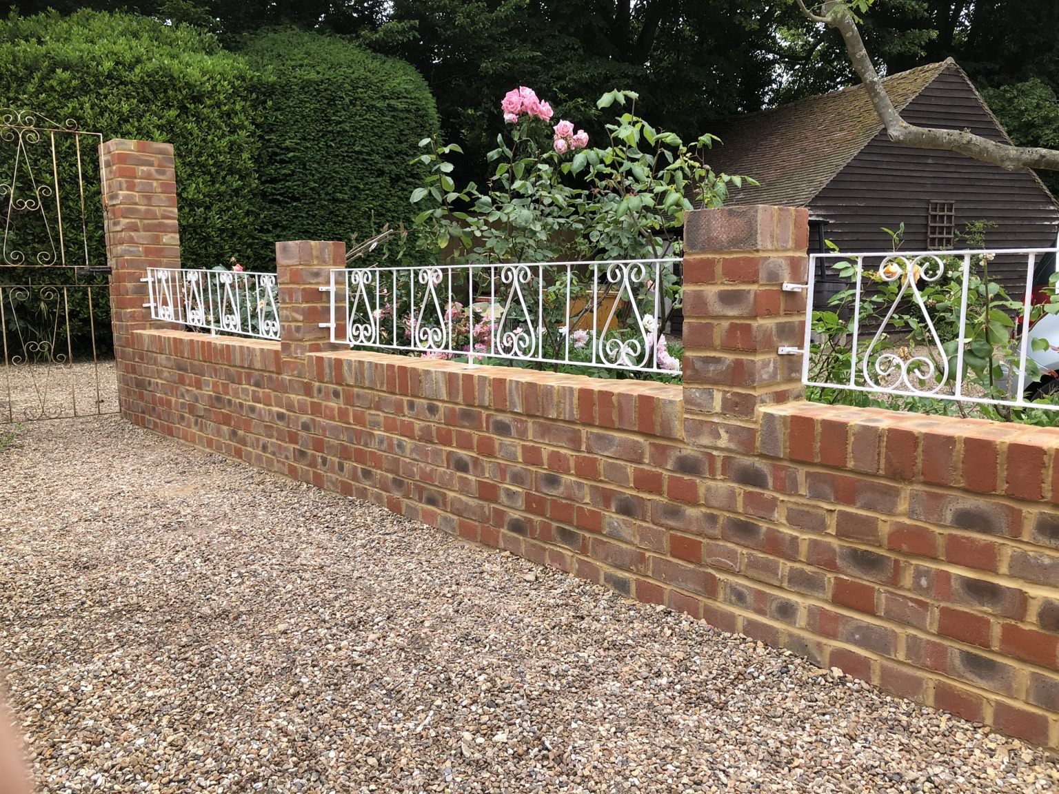 Finished garden wall with brick piers and white metal railings